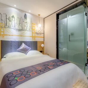 Une chambre d’hôtel avec un lit, une fresque représentant un paysage urbain, une porte en verre et une table de chevet avec une lampe.