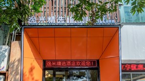 A building with a sign in Chinese characters, a glass door entrance, and a reflection of a street scene.