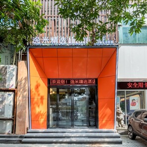 L’entrée d’un hôtel, avec une façade orange et un panneau d’affichage numérique.