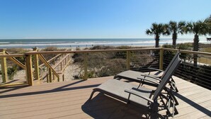 A wooden deck with lounge chairs overlooking a beach. - Oceanfront home with Hot tub and pool table~ 915 W Ashley (Folly Beach)