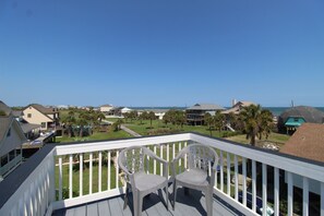 A balcony with two chairs overlooking a residential area with houses and a view of the ocean. - River and Ocean Views Expansive Interior 1505 Forrest Ave (Folly Beach)