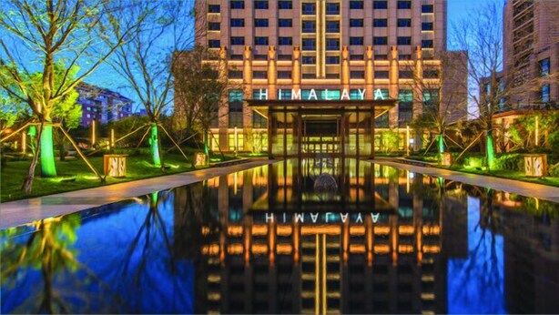 A modern hotel with a reflective pool in front, surrounded by greenery and illuminated pathways. - Himalaya Serviced Residences Nankai Tianjin (Tianjin)