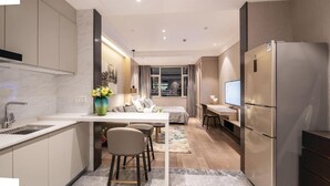 A modern kitchen with a central island, a dining area, a bedroom with a large window, and a built-in refrigerator. - Himalaya Serviced Residences Nankai Tianjin (Tianjin)