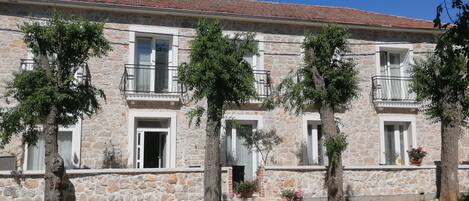 A stone building with a tiled roof, multiple windows, and balconies.