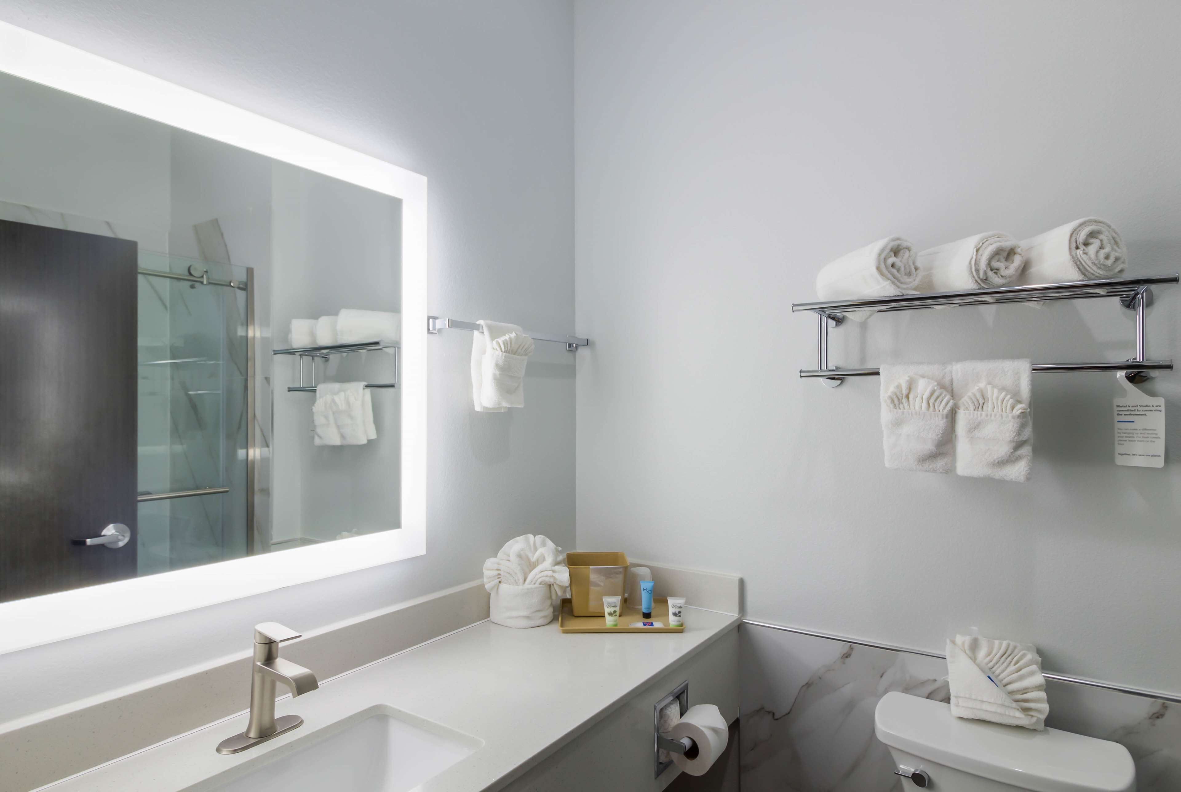 Une salle de bain moderne avec un grand miroir, deux lavabos, des toilettes et des porte-serviettes.