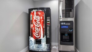 Una máquina expendedora de Coca-Cola y un dispensador de hielo en una esquina.