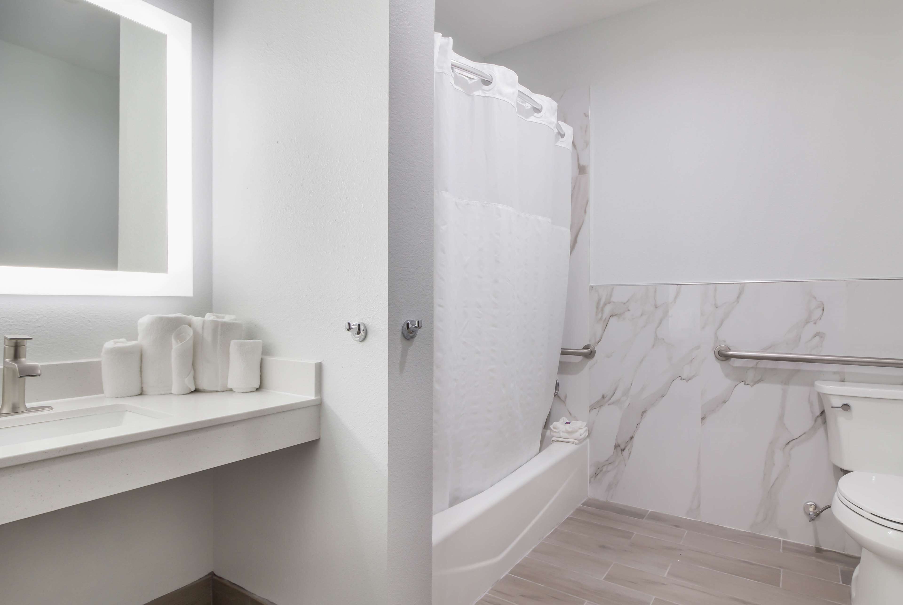 A bathroom with a white sink, mirror, and marble walls.