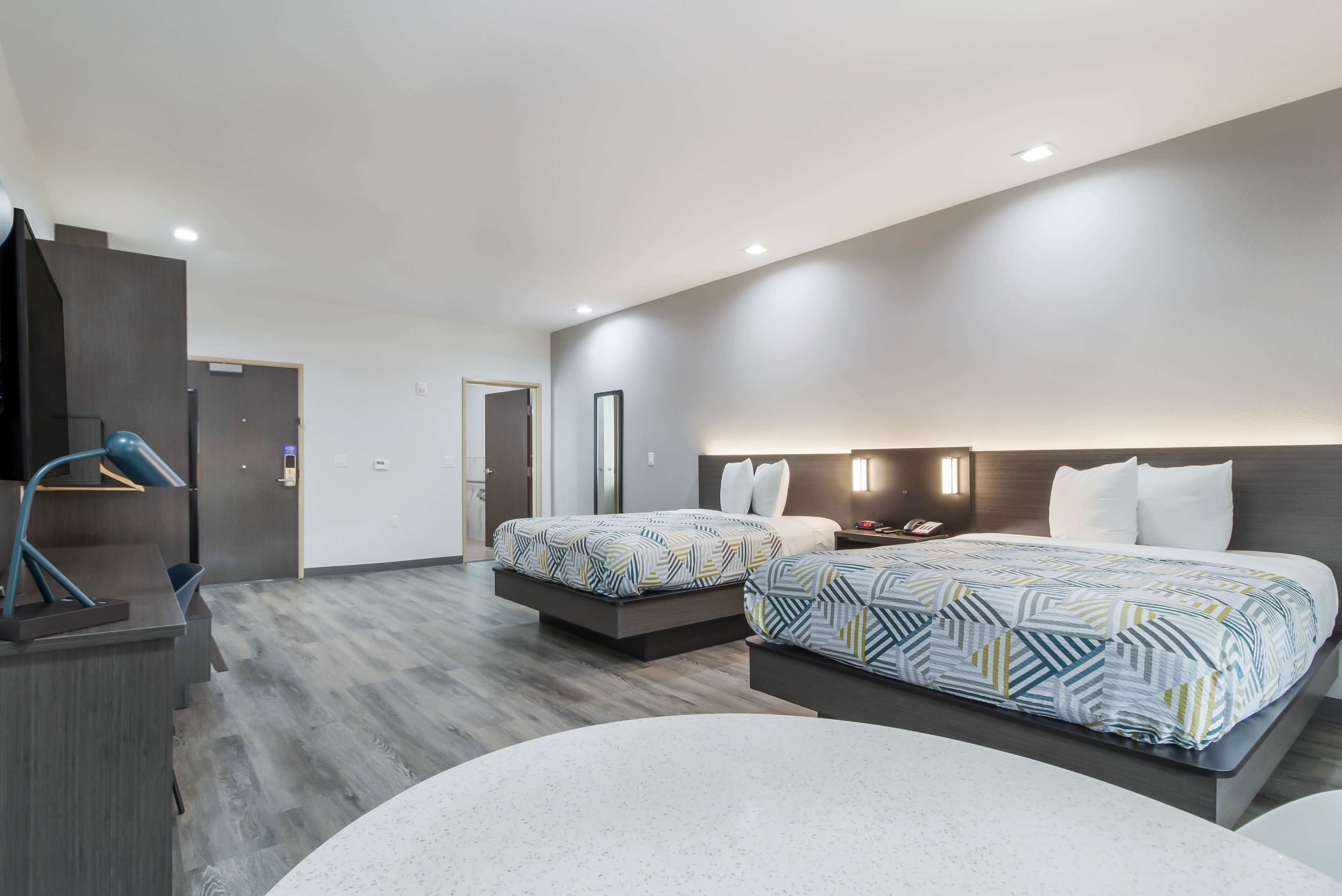 A modern hotel room with two beds, a desk, and a seating area.
