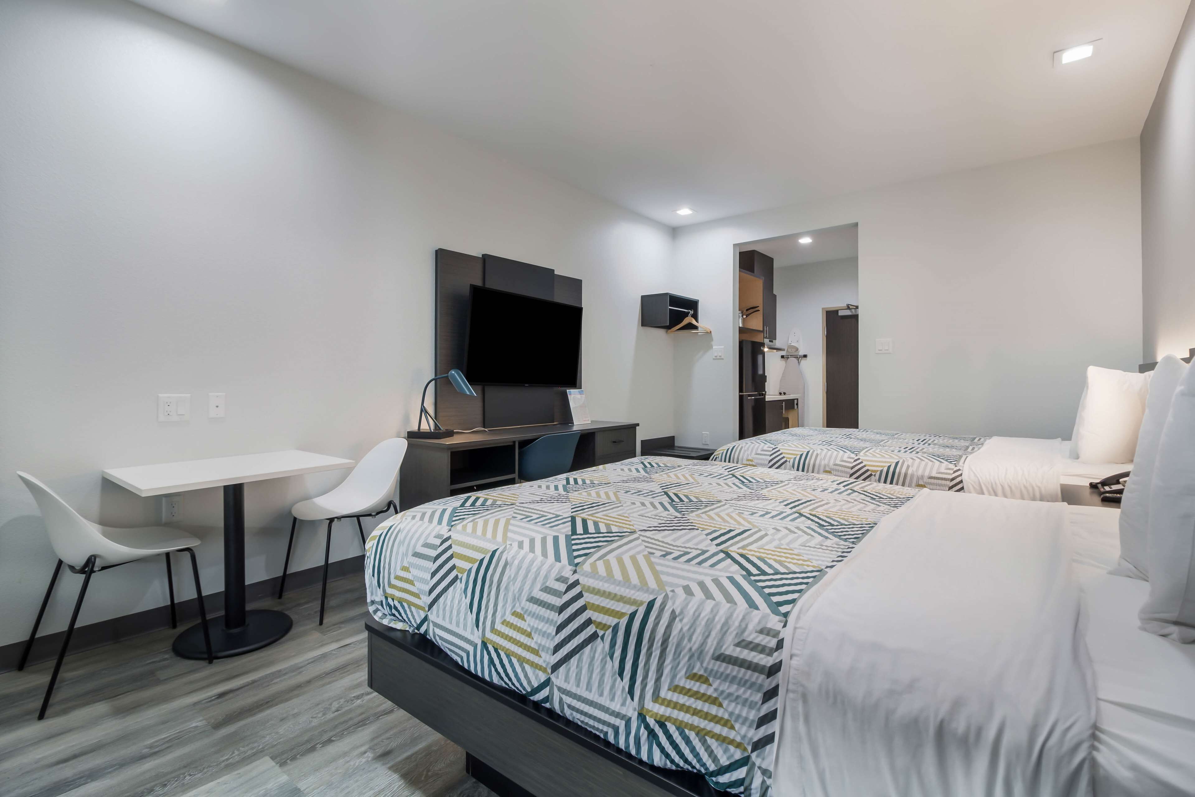 A hotel room with a bed, a desk, a chair, a TV, and a bathroom.