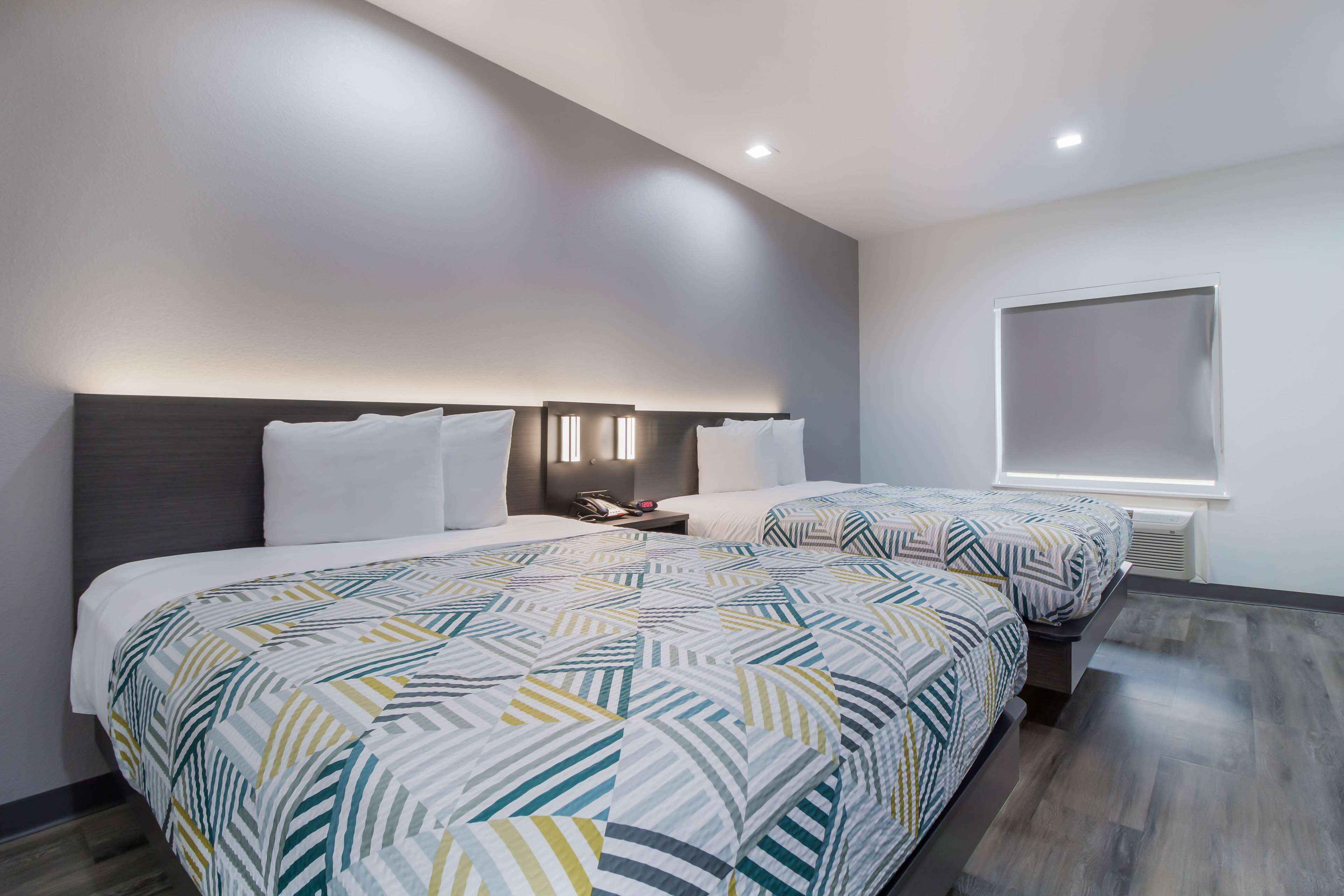 Et moderne hotelværelse med to senge, et natbord og et stort vindue.