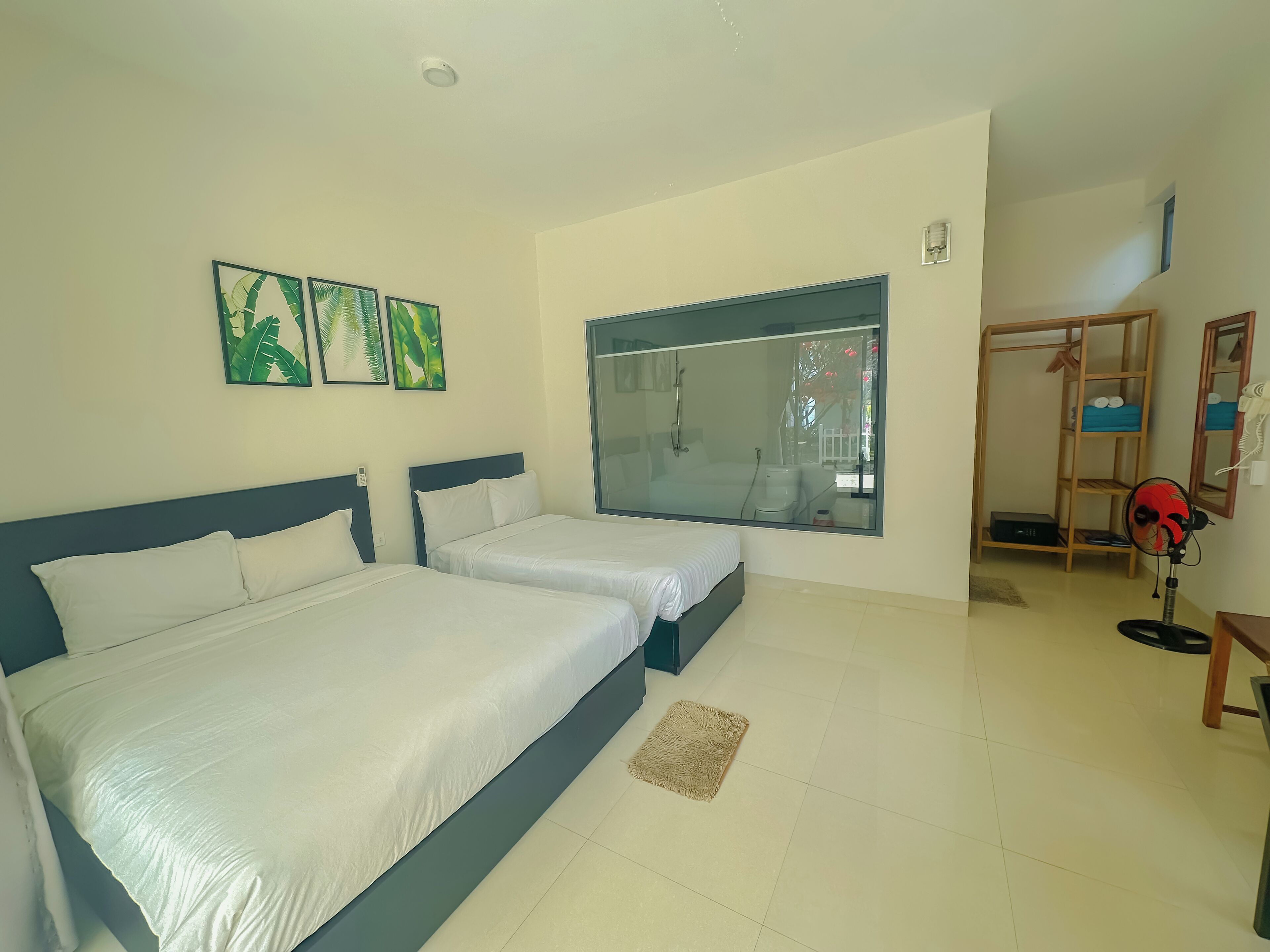 A hotel room with two beds, a large window, and a wooden wardrobe.
