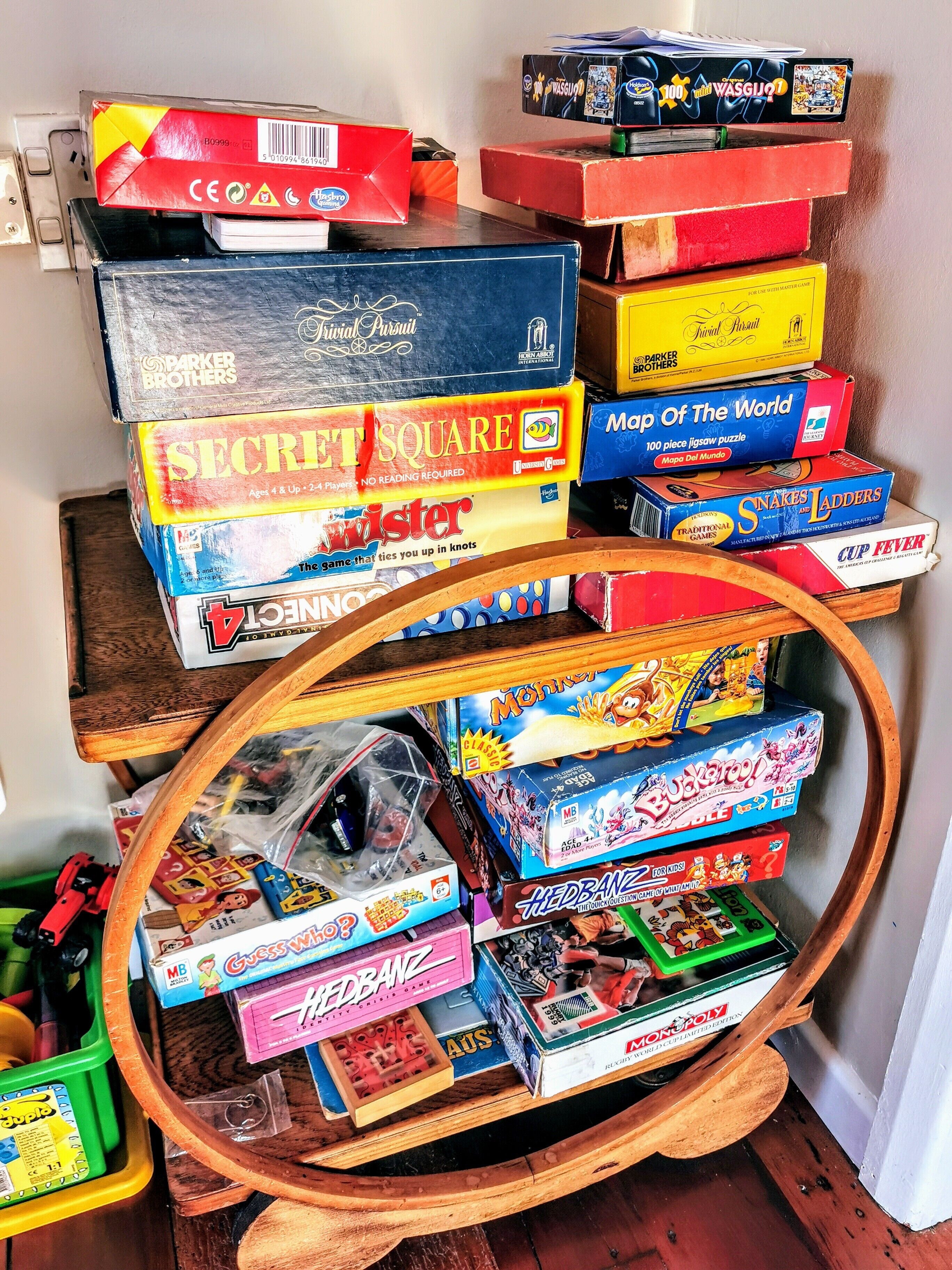 A collection of board games and puzzles on a shelf and a wooden stand.