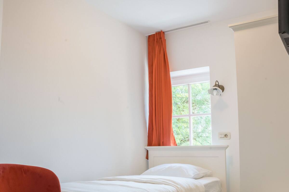 Una habitación pequeña y limpia con una cama, un escritorio y una silla.