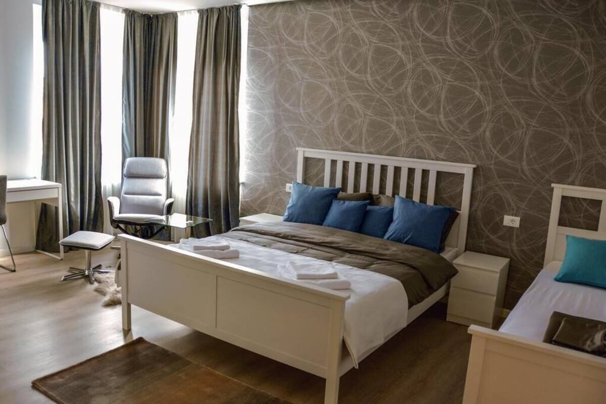Un dormitorio con cama, mesitas de noche, un escritorio y una silla.