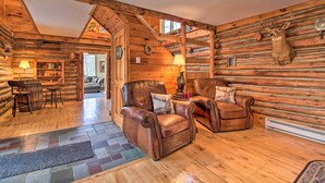 A log cabin interior with leather armchairs, a fireplace, and a mounted deer head. - Spacious Mtn Cabin on 7 Private Acres in Athol! (Athol)