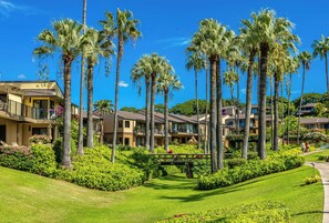 A resort with multiple-story buildings, palm trees, and well-maintained lawns.