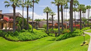 A resort with multiple-story buildings, palm trees, and well-maintained lawns. - Cozy Treasure Nestled on a Lush Oceanfront Property - Wailea Elua 1508 (Wailea, Maui)
