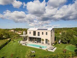 Uma casa moderna de dois andares com piscina, área de estar ao ar livre e um campo de golfe ao fundo.
