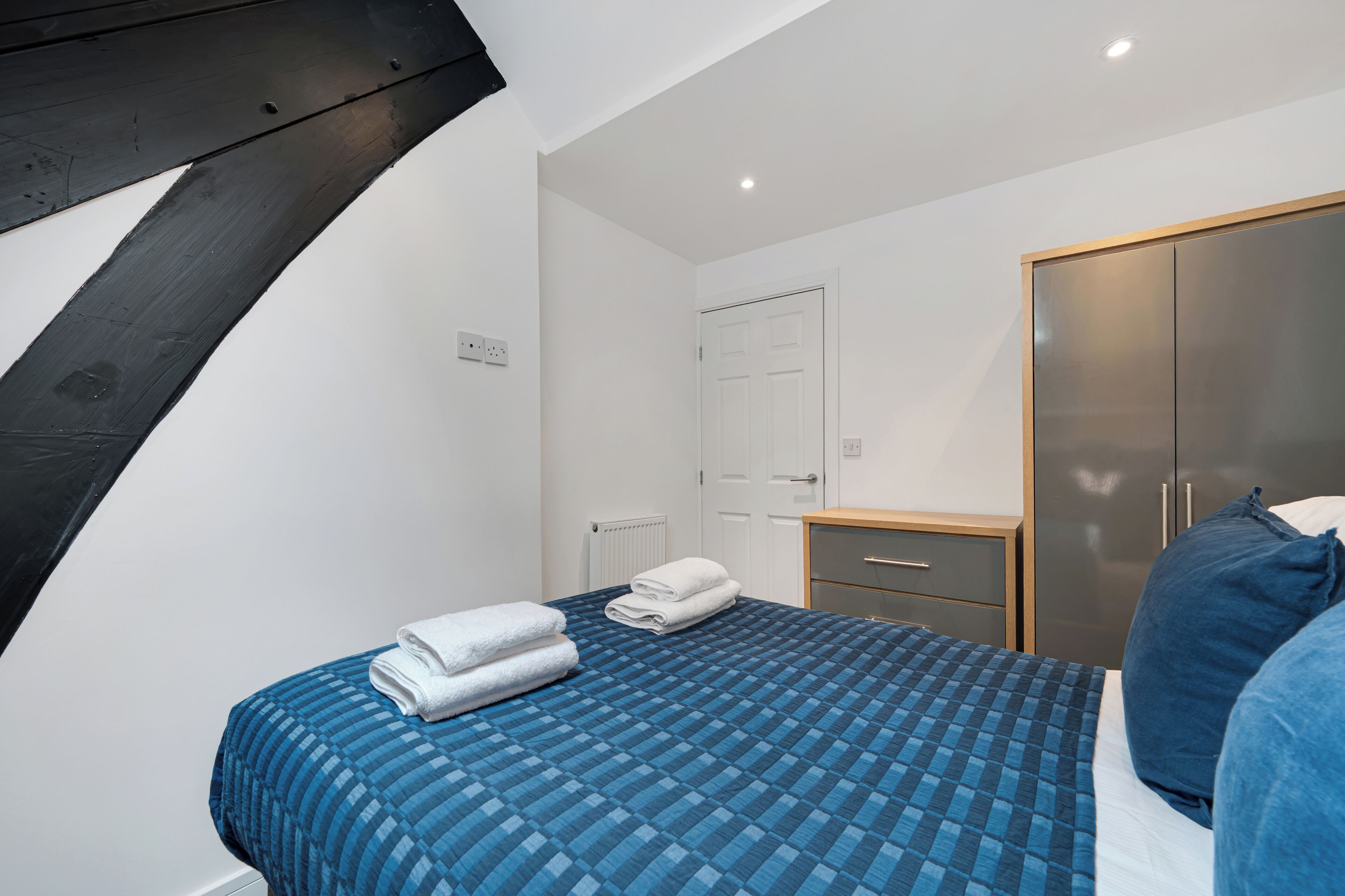 Une chambre à coucher avec un lit, une armoire, une table de chevet et une porte.