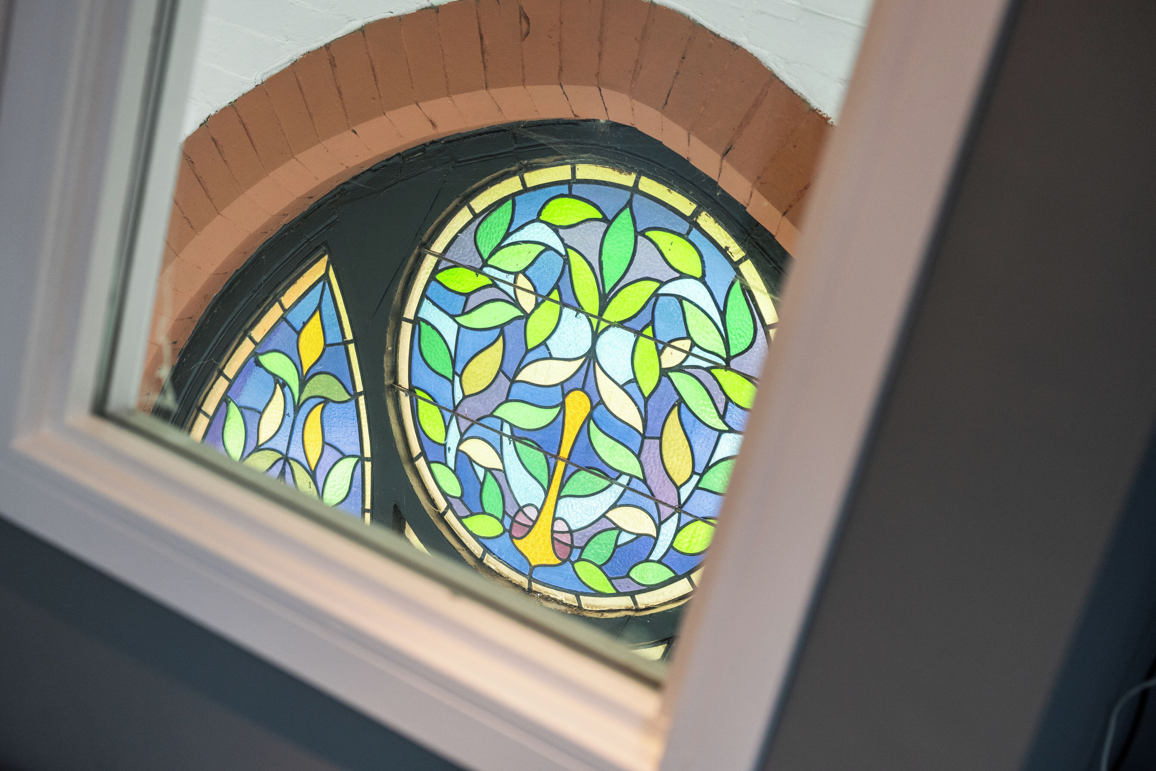 A window with a view of a brick archway and a stained glass window.