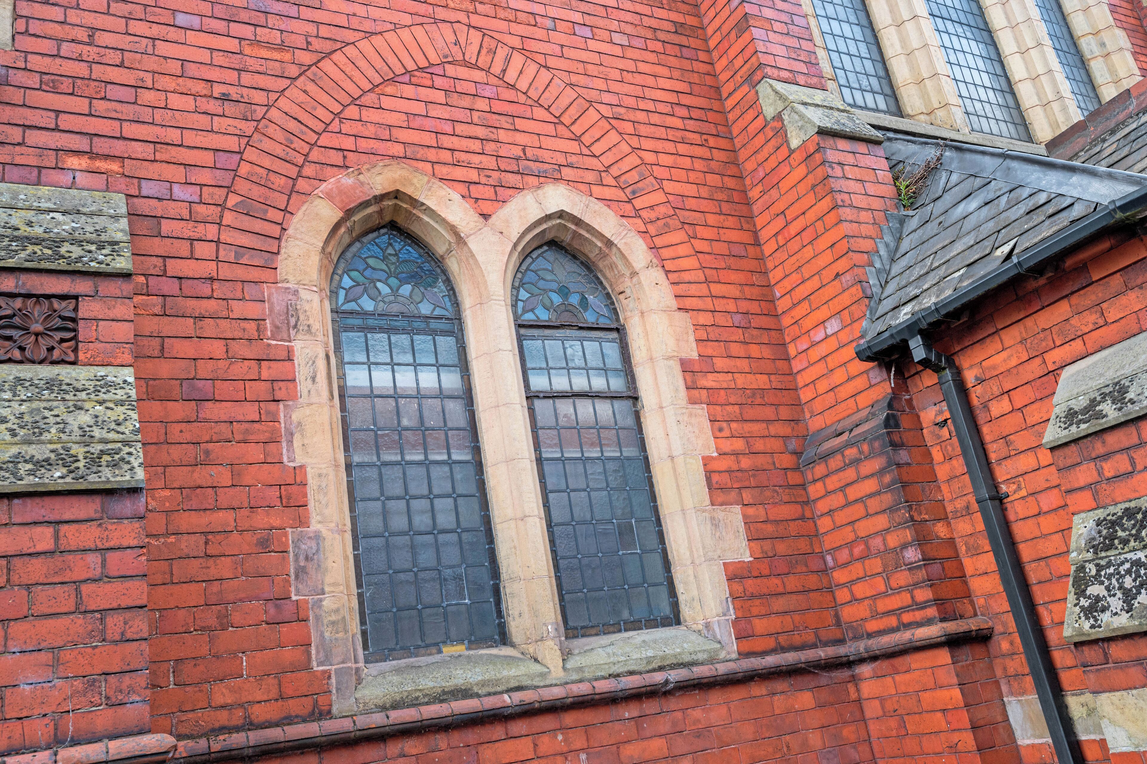 A red brick building with a large arched window and a smaller window below it.