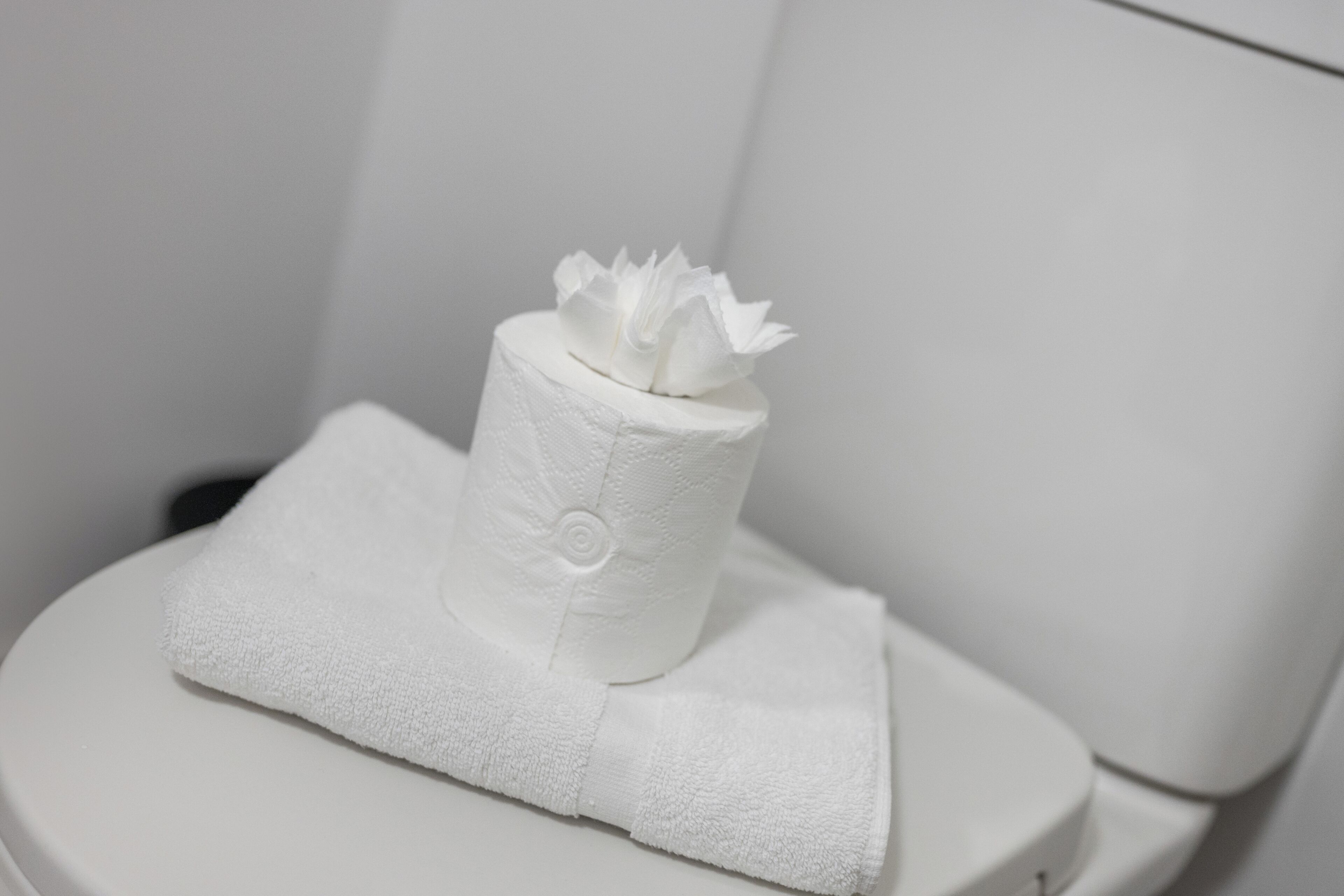 A toilet with a white towel and a toilet paper holder.