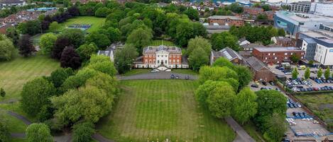An aerial view of a large estate with a central building, surrounded by lush greenery and a well-maintained lawn.