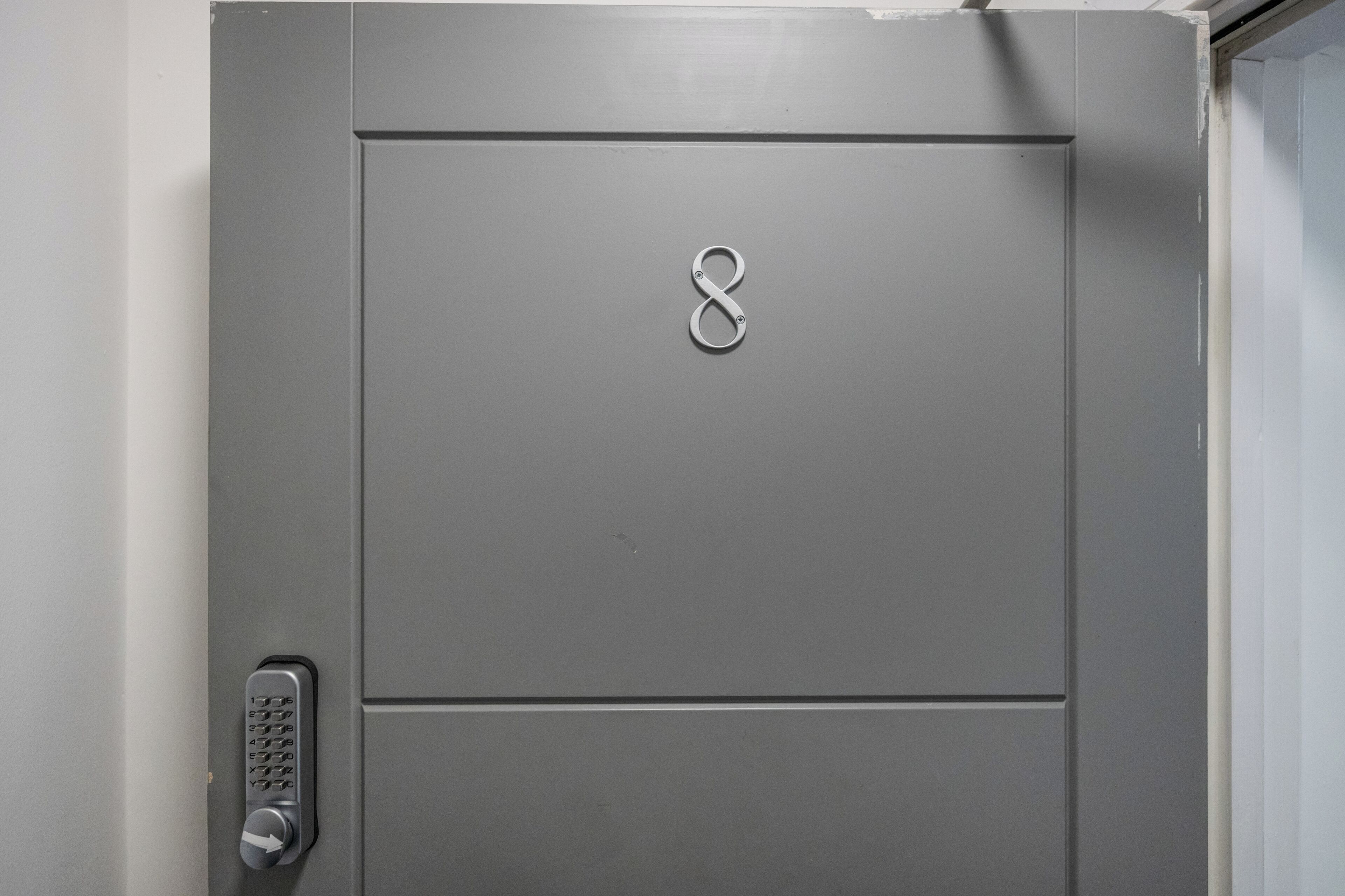 Una puerta gris con teclado numérico y cerradura.