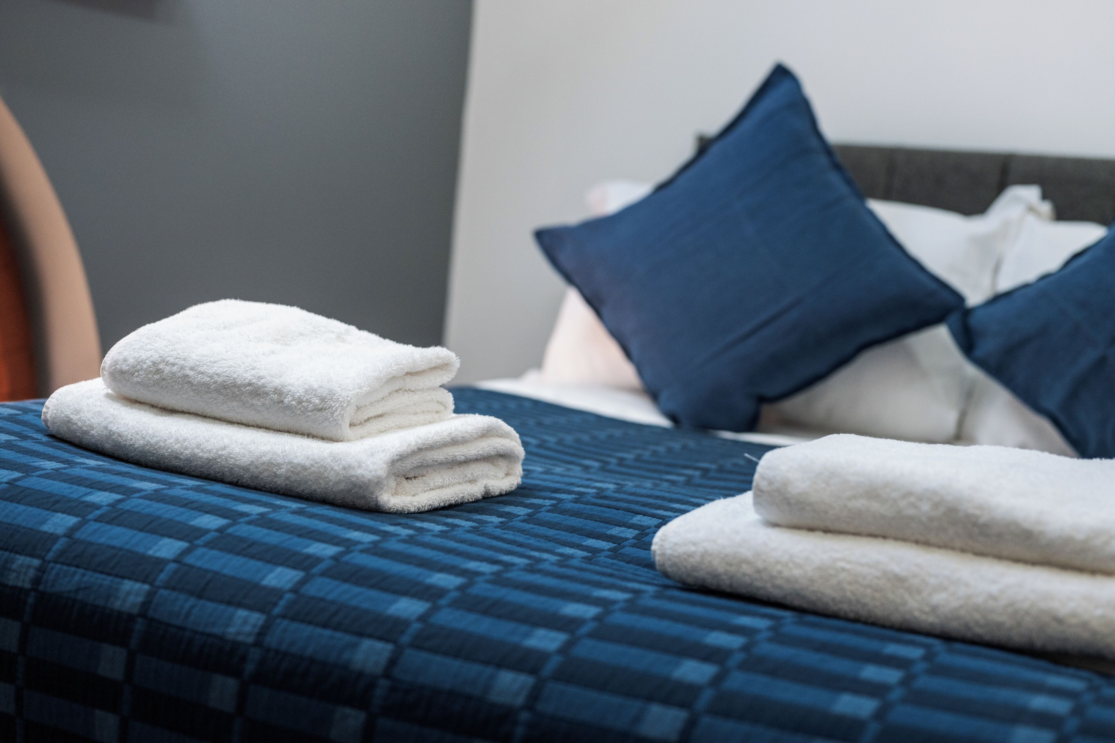 A neatly made bed with blue bedding and white towels.