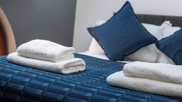 A neatly made bed with blue bedding and white towels.