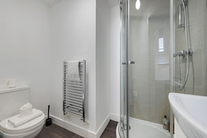 Un baño moderno con ducha de vidrio, inodoro blanco y barra para toallas.