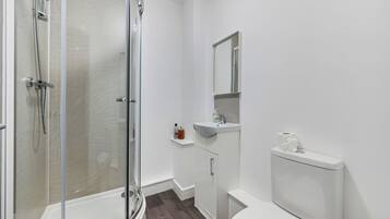 Un baño con ducha de vidrio, inodoro, lavabo y espejo.