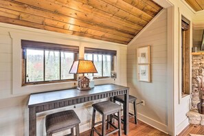 A cozy room with a wooden ceiling, a small table with two stools, a lamp, and a window with blinds. - Putt-Putt, Pickleball + Trails: Glenville Getaway (Glenville)