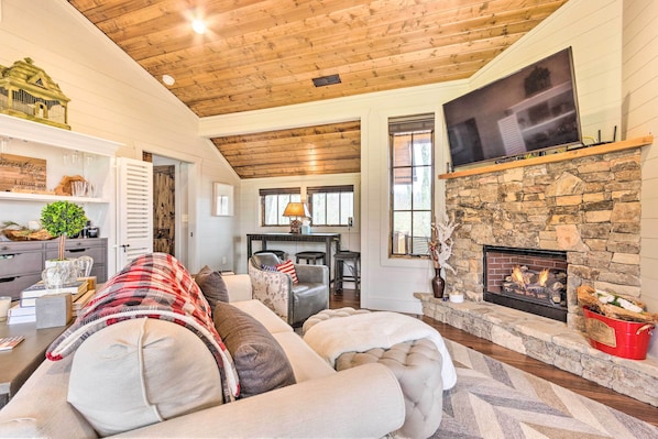 A cozy living room with a stone fireplace, a flat-screen TV, and a comfortable couch. - Putt-Putt, Pickleball + Trails: Glenville Getaway (Glenville)