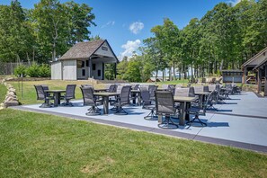 An outdoor patio area with multiple tables and chairs, a small building, and a stone wall. - Putt-Putt, Pickleball + Trails: Glenville Getaway (Glenville)