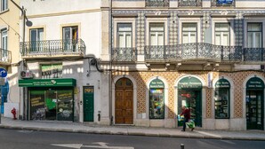 Vista de la calle de un edificio con varias tiendas, incluyendo una agencia de crédito y una ferretería.