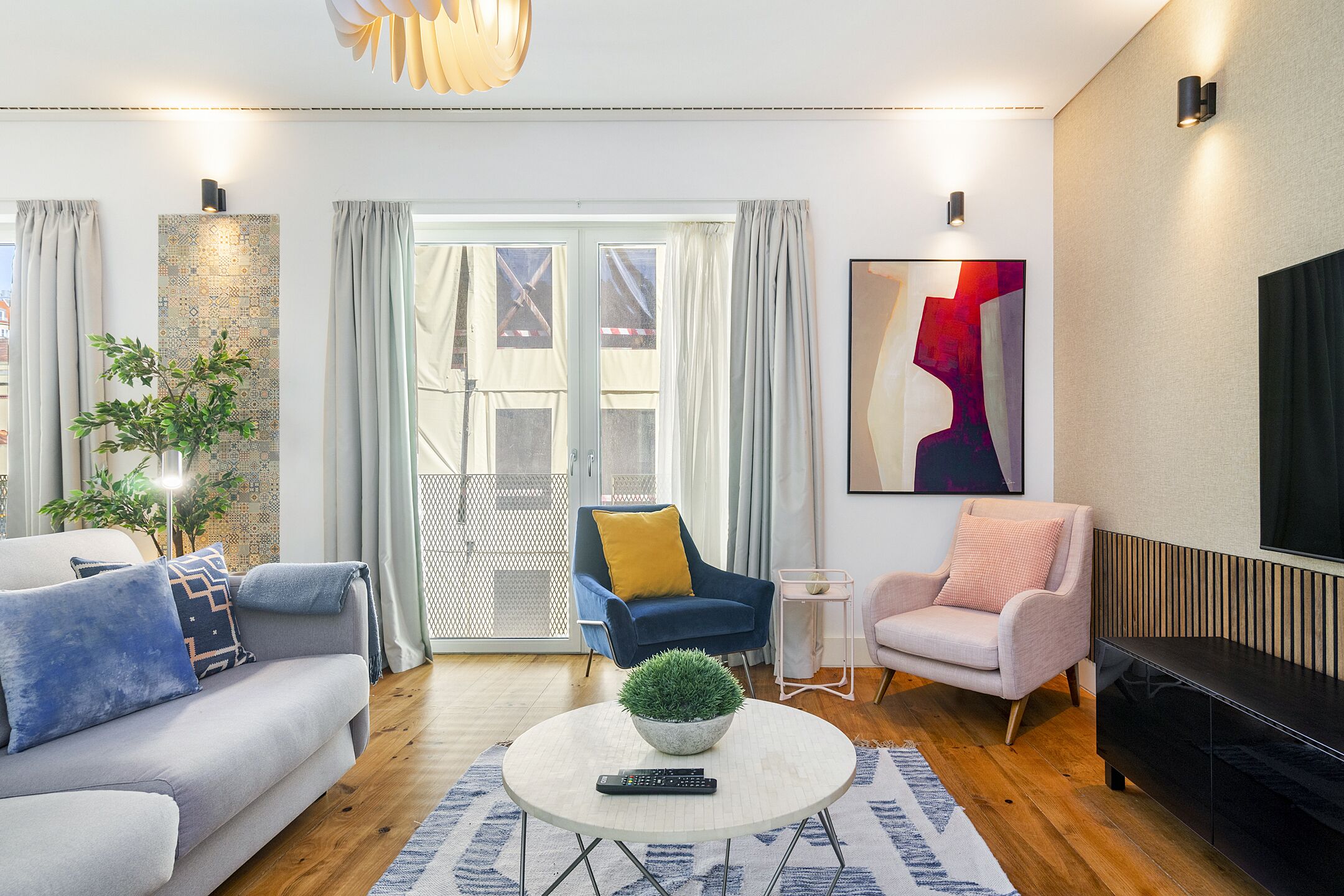 Una sala de estar moderna con un sofá, sillones, una mesita de centro y un televisor.