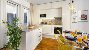 Una cocina moderna con armarios blancos, un microondas y un comedor con una mesa dispuesta para el desayuno.