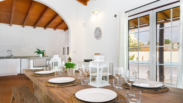 A dining area with a wooden table set for four, surrounded by white plates, cutlery, and glasses. - Comporta Family Beach House (Alcacer do Sal)