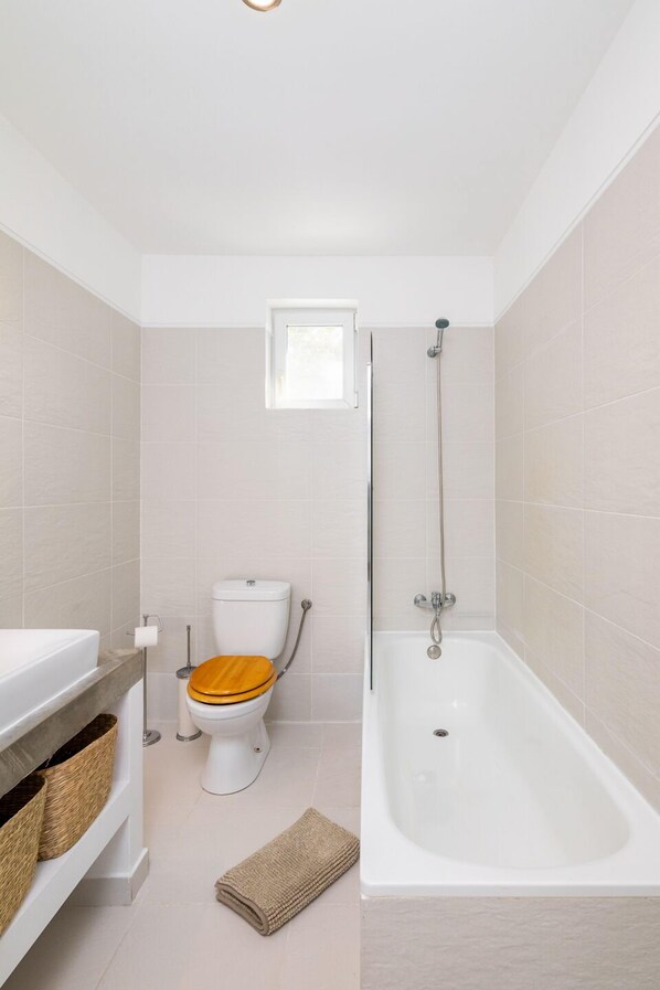 Un baño con inodoro, bañera y ventana.