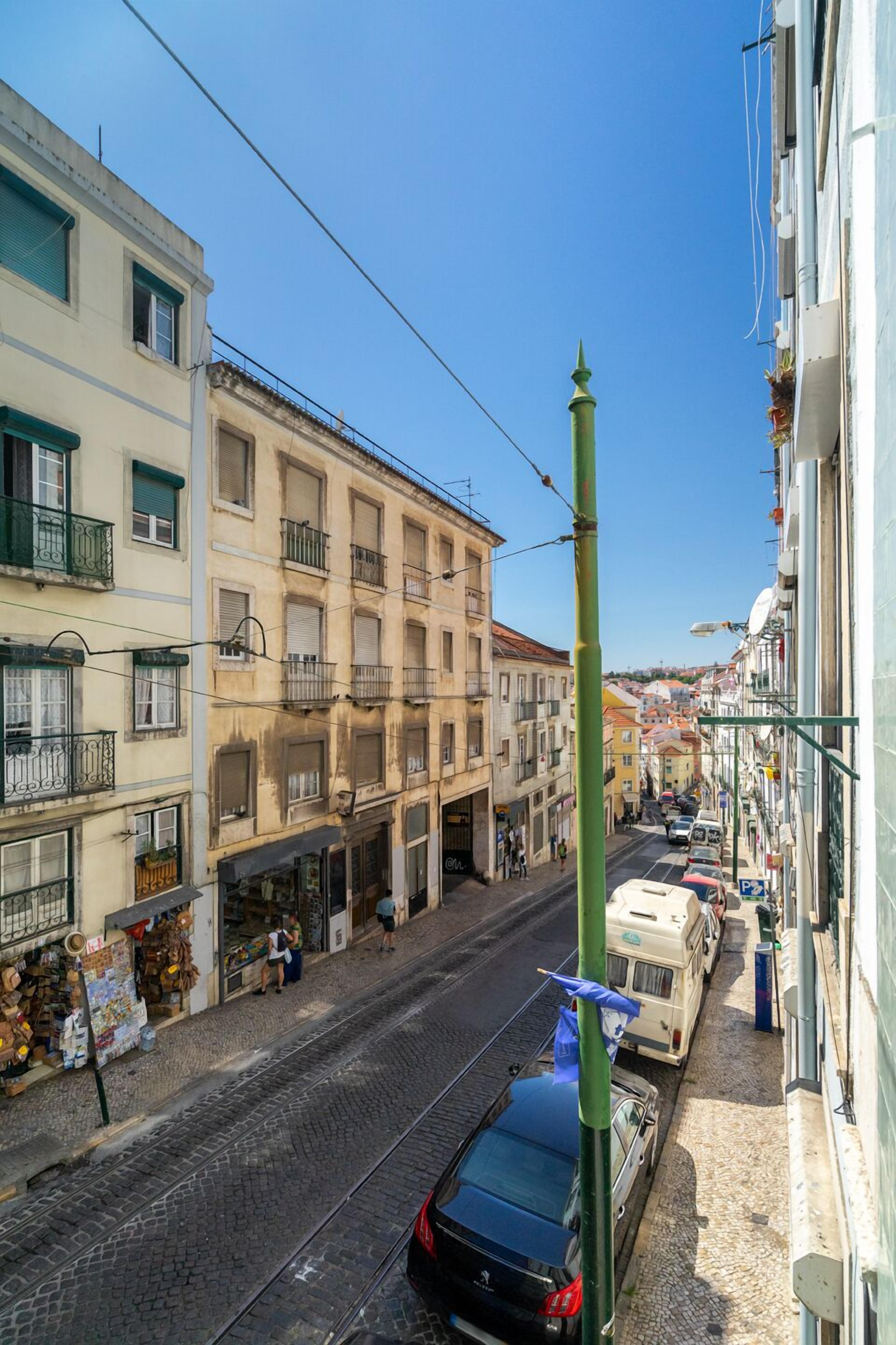Eine Straße mit Gebäuden an beiden Seiten, eine Straßenbahn und ein geparktes Auto.