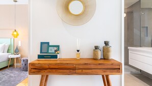 Une salle de bain moderne avec une douche à parois de verre, un meuble-lavabo blanc et une console en bois agrémentée d’objets décoratifs.