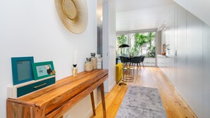 Une cuisine moderne avec des meubles blancs, une table à manger en bois et une grande fenêtre donnant sur un paysage verdoyant.