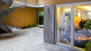 A courtyard with a spiral staircase, cobblestone floor, and a glass door leading to a dining area. - LS48 Prime Location Upscale Apartment (Lisbon)