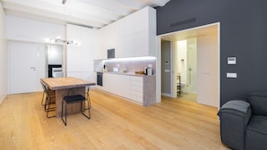 A modern kitchen with a wooden dining table and chairs, a built-in oven, and a dark accent wall. - LS48 Prime Location Upscale Apartment (Lisbon)