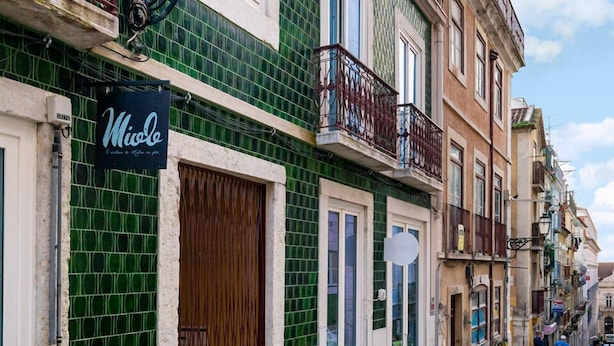 A street with a green building featuring a sign that reads "Mio de". - LS48 Prime Location Upscale Apartment (Lisbon)