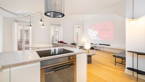 A modern kitchen with a built-in stove, wooden flooring, and pendant lighting.