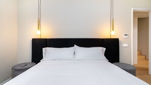 A modern hotel room with a large bed, two bedside tables, and a black headboard.