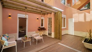 An outdoor patio with wooden flooring, white wicker furniture, and a potted plant. - Hideaway Family Apartment (Lisbon)