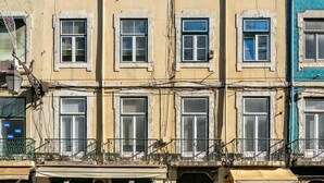 Un edificio de varios pisos con una tienda en la planta baja y un balcón visible.